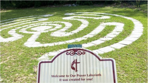 A picture of NEUMC's prayer labyrinth. It has the prayer labyrinth, and the sign for the prayer labyrinth.