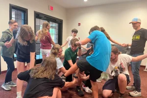 A group of youth members play the human knot game in the education building