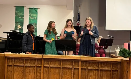 A few youth group members play handbells during the Christmas Eve 2023 service.