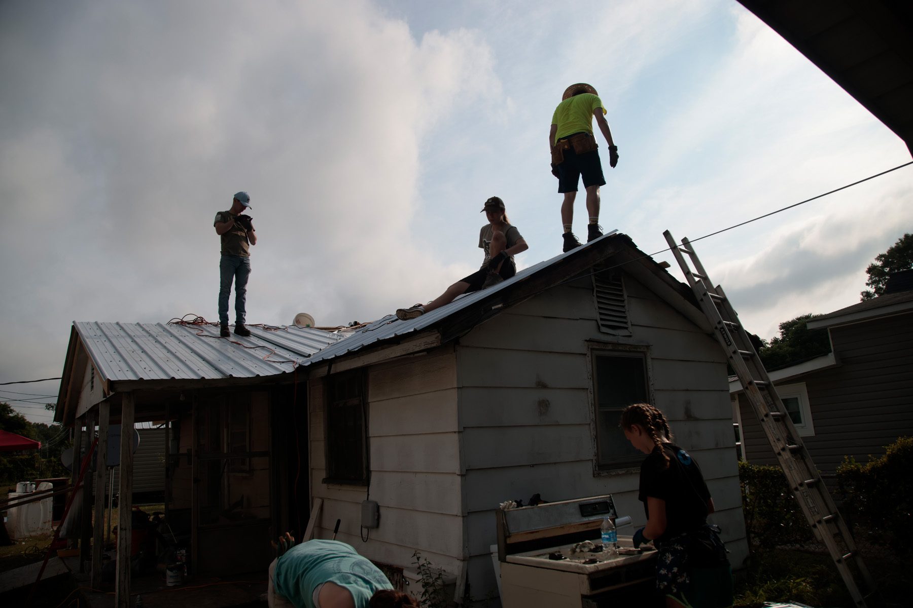 3 Salkehatchie 2024 volunteers are standing on a newly installed tin roof.